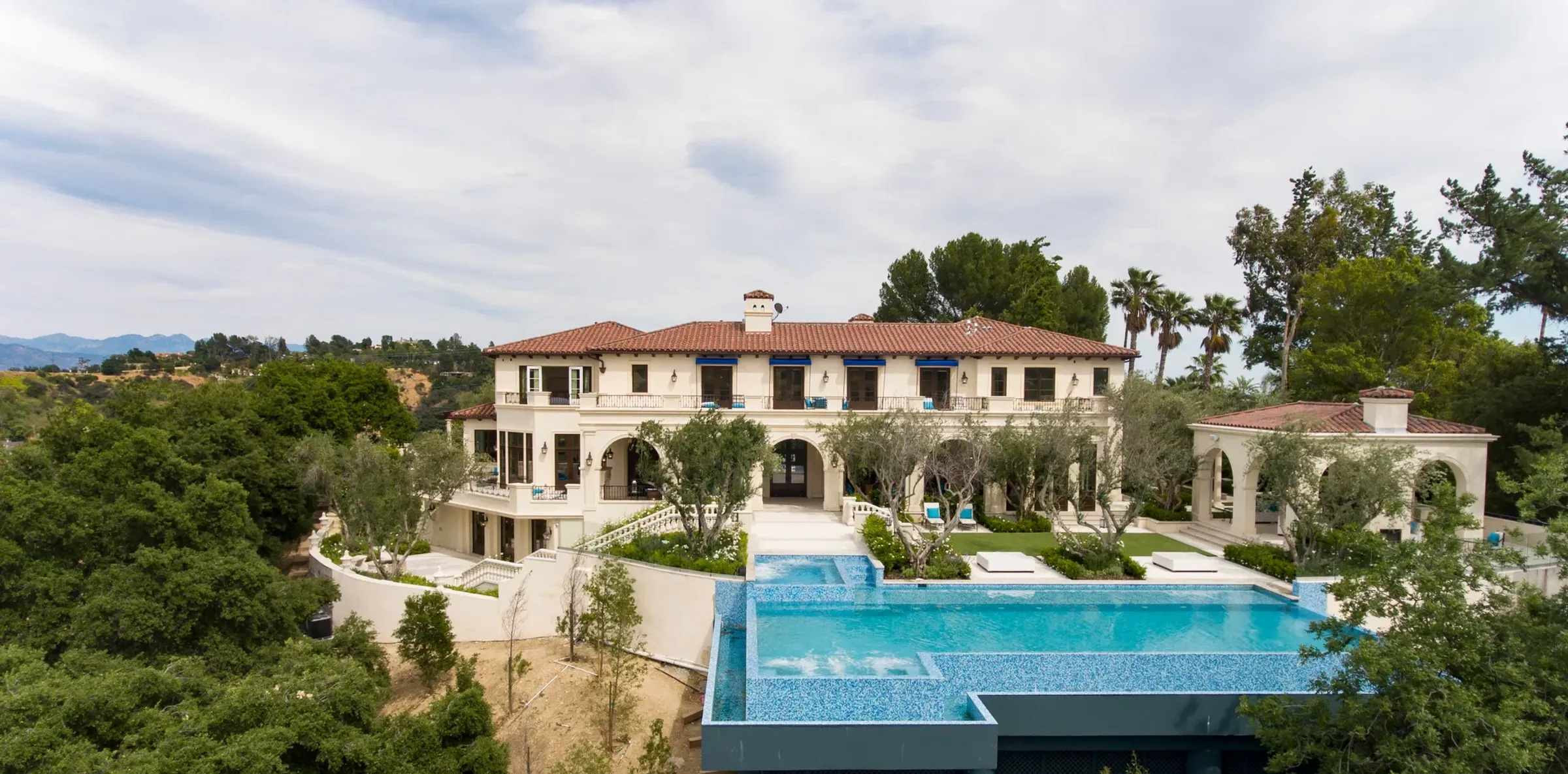 Aerial view of a Mediterranean estate with an infinity pool above the canyon