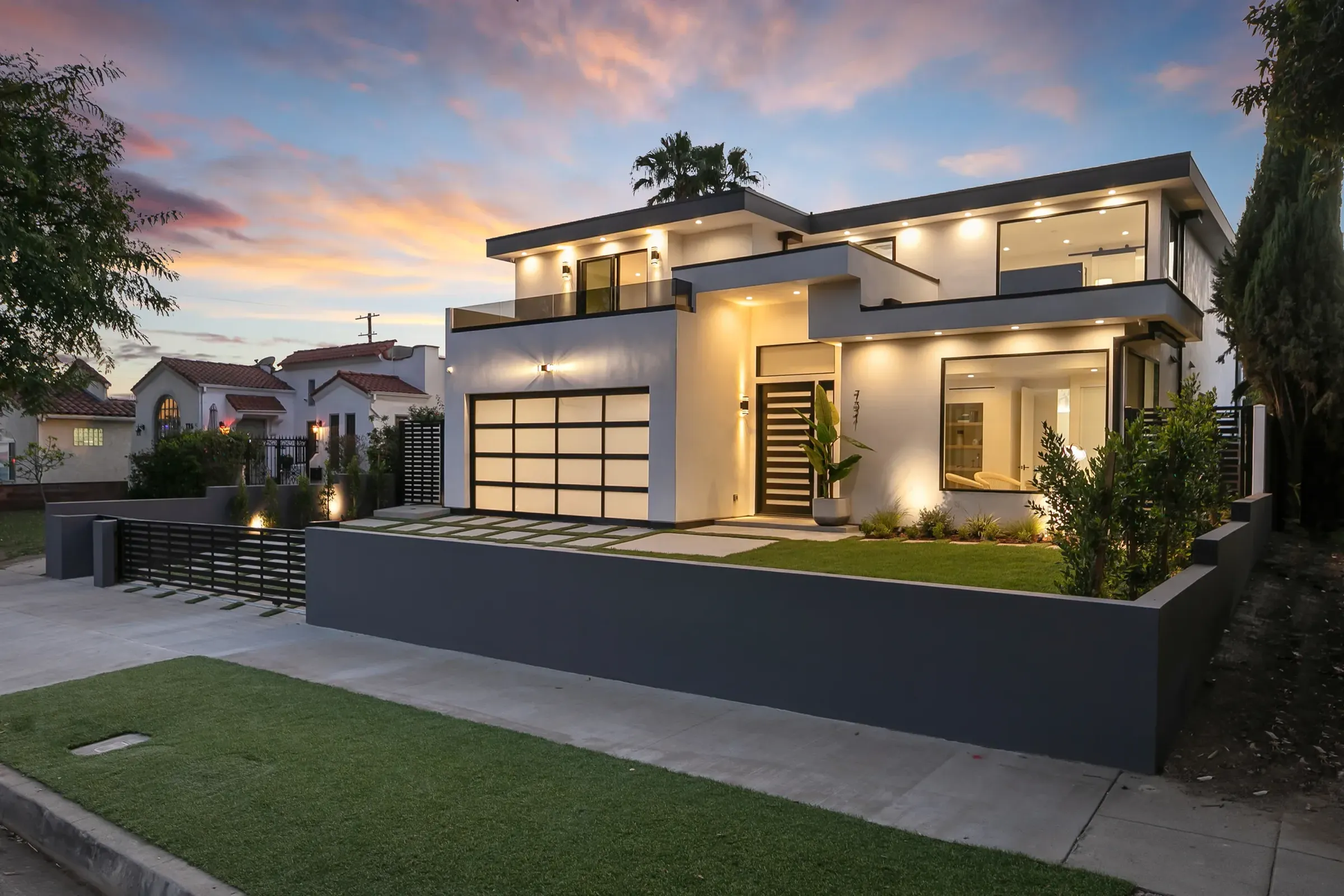 New two-story modern home with a glass garage door, lit up at sunset
